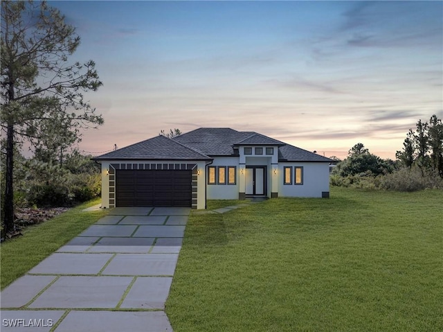 1220 Edison Ave, Lehigh Acres, FL 33972 - prairie-style house featuring a front yard, roof with shingles, driveway, stucco siding, and a garage