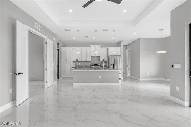 unfurnished living room featuring light tile patterned flooring, ceiling fan, and a raised ceiling