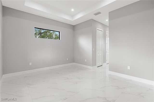 tiled spare room featuring a raised ceiling