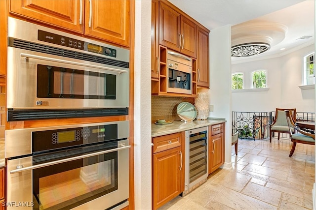 kitchen with decorative backsplash, light stone counters, light tile patterned flooring, ornamental molding, and beverage cooler