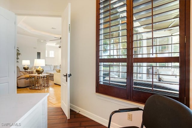 interior space with ceiling fan, a tray ceiling, and hardwood / wood-style flooring