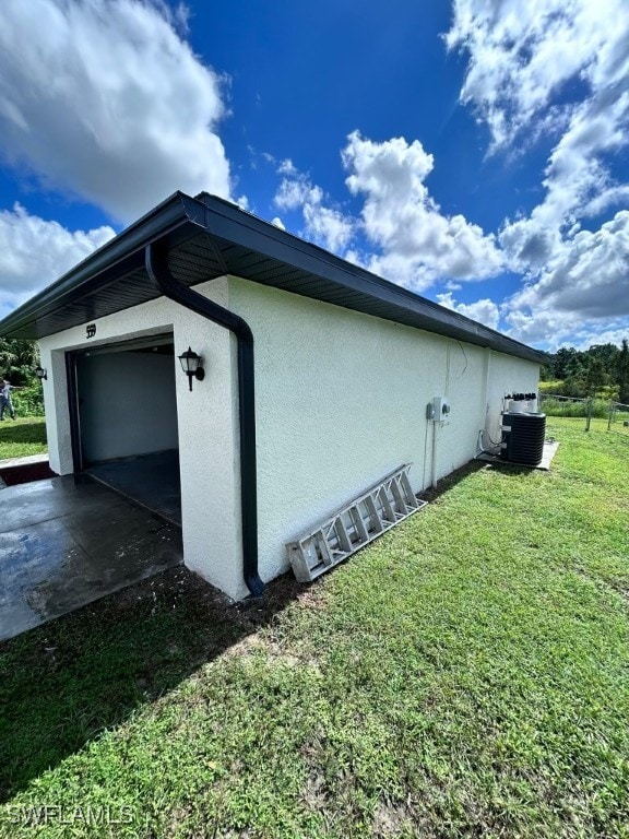 view of side of home with cooling unit, a lawn, and a garage