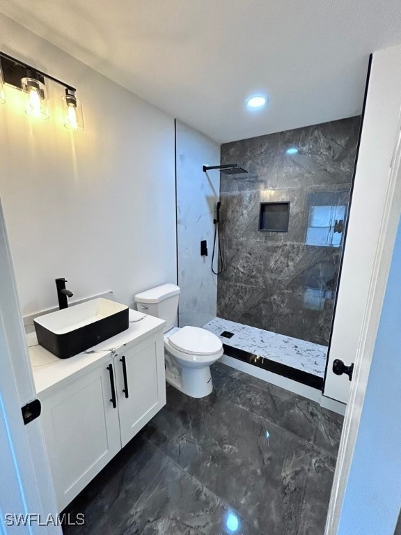 bathroom featuring tiled shower, vanity, and toilet