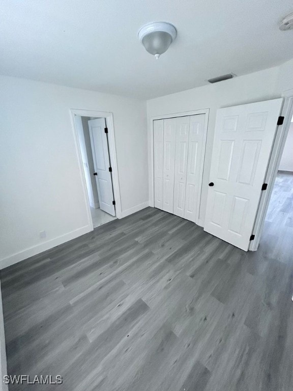 unfurnished bedroom with dark wood-type flooring and a closet