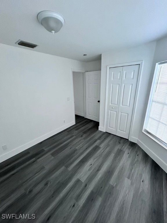 unfurnished bedroom with dark wood-type flooring and a closet