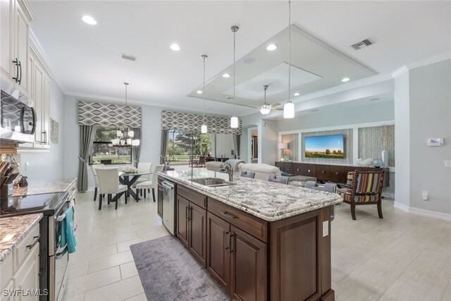 kitchen featuring white cabinets, pendant lighting, stainless steel appliances, dark brown cabinetry, and a kitchen island with sink