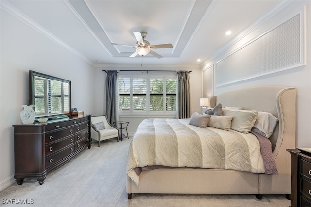 carpeted bedroom featuring ceiling fan, a raised ceiling, and ornamental molding