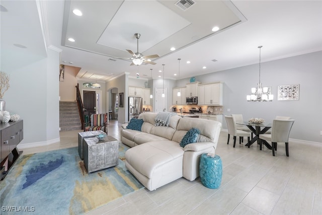 living room featuring ceiling fan with notable chandelier and ornamental molding