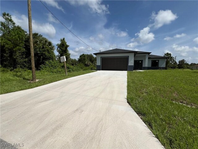 view of front of home with concrete driveway, an attached garage, a front yard, and stucco siding