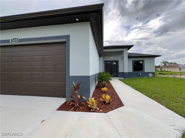 view of front of house with concrete driveway, an attached garage, a front yard, and stucco siding