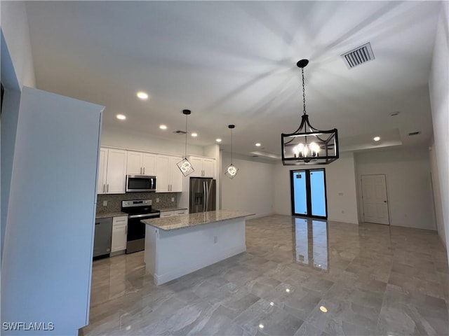 kitchen featuring visible vents, a center island, a notable chandelier, white cabinets, and stainless steel appliances