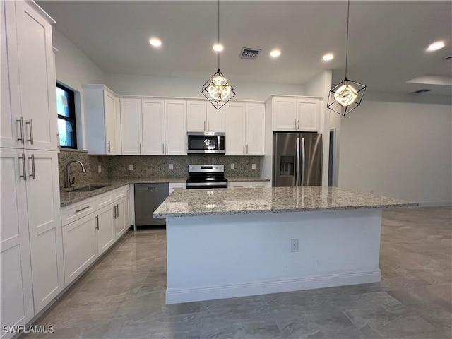 kitchen with tasteful backsplash, a kitchen island, appliances with stainless steel finishes, white cabinets, and a sink