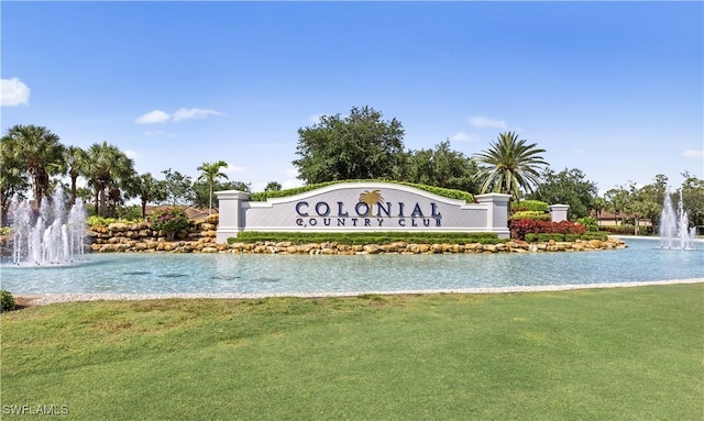 community / neighborhood sign featuring a water view and a yard