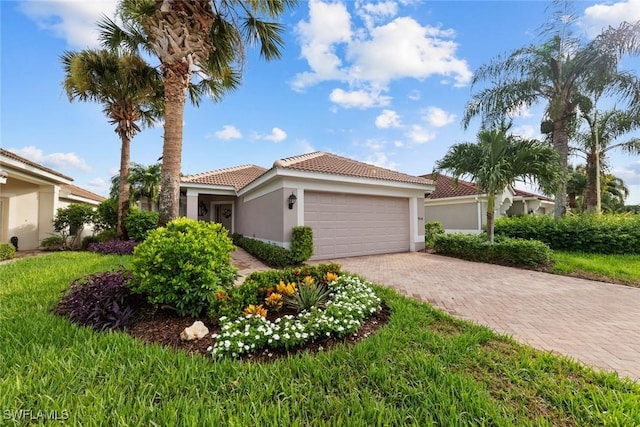 mediterranean / spanish house featuring a garage, stucco siding, a tile roof, decorative driveway, and a front yard