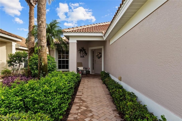 property entrance with stucco siding and a tile roof