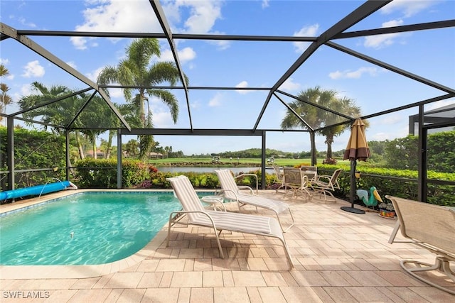 pool with glass enclosure, a patio, and a water view