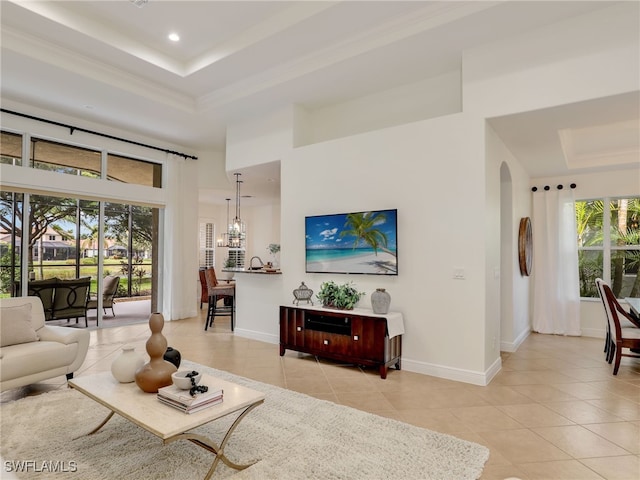 living room featuring a raised ceiling, crown molding, a towering ceiling, a chandelier, and light tile patterned flooring