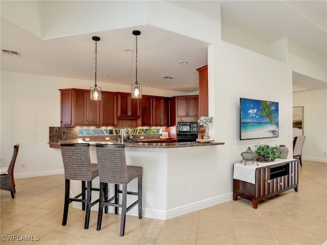 kitchen featuring backsplash, black appliances, decorative light fixtures, kitchen peninsula, and a breakfast bar area