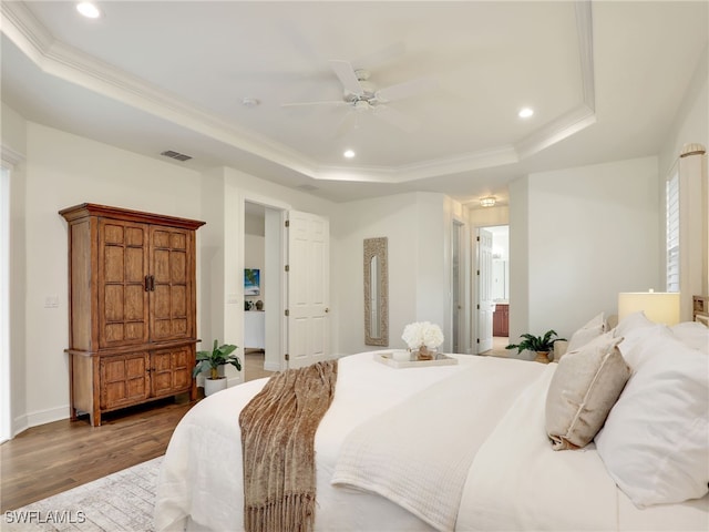 bedroom featuring a tray ceiling, ceiling fan, crown molding, and dark hardwood / wood-style floors