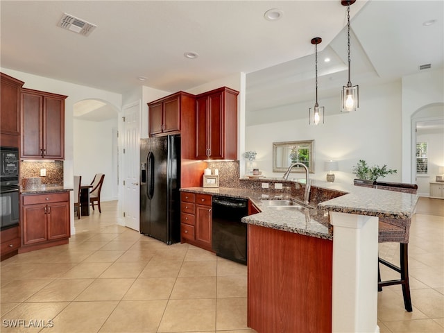 kitchen featuring a kitchen bar, tasteful backsplash, sink, black appliances, and hanging light fixtures