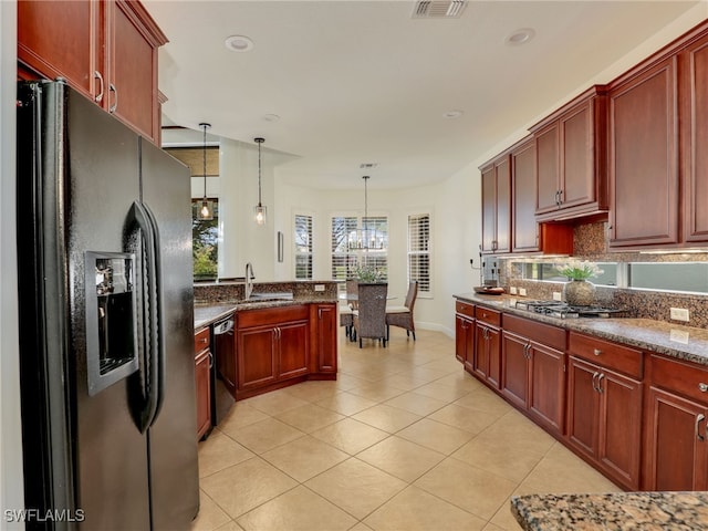 kitchen with dark stone counters, sink, black appliances, pendant lighting, and a chandelier