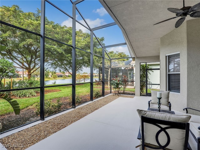 sunroom with ceiling fan and a water view