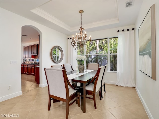 tiled dining area with a tray ceiling, crown molding, and a chandelier