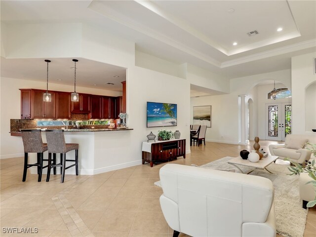 living room with light tile patterned floors, a tray ceiling, and french doors