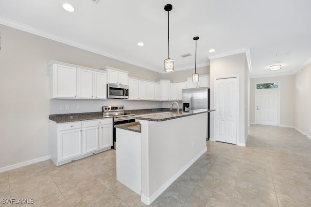 kitchen with appliances with stainless steel finishes, a kitchen island with sink, ornamental molding, light tile patterned floors, and white cabinets