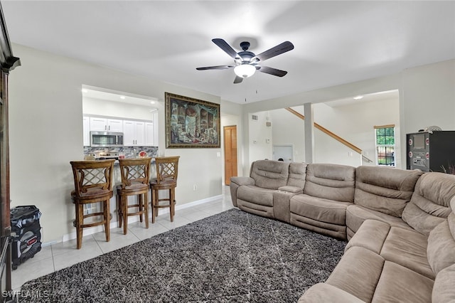 living room featuring light tile patterned floors, baseboards, and a ceiling fan