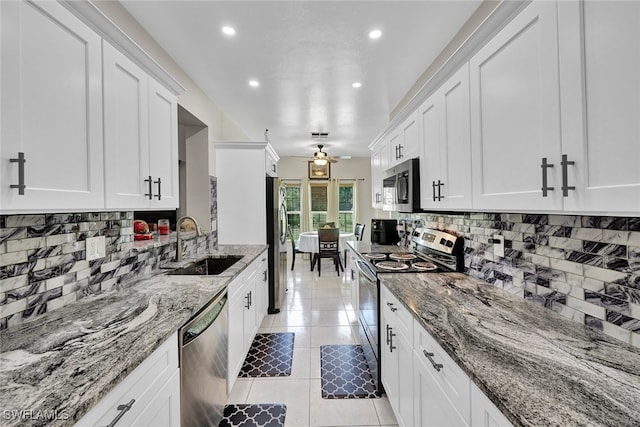 kitchen with ceiling fan, light stone countertops, stainless steel appliances, and light tile patterned floors