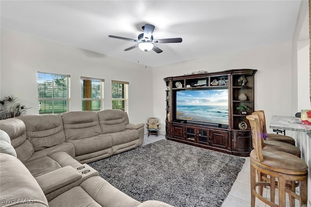 living area with light tile patterned floors and a ceiling fan