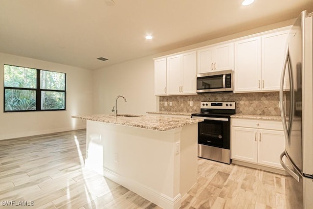 kitchen featuring white cabinets, stainless steel appliances, a center island with sink, and sink