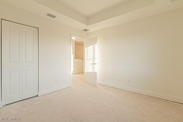 unfurnished bedroom featuring a tray ceiling and a closet