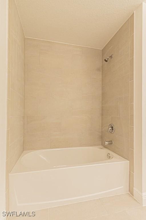 bathroom with tile patterned flooring, tiled shower / bath, and a textured ceiling