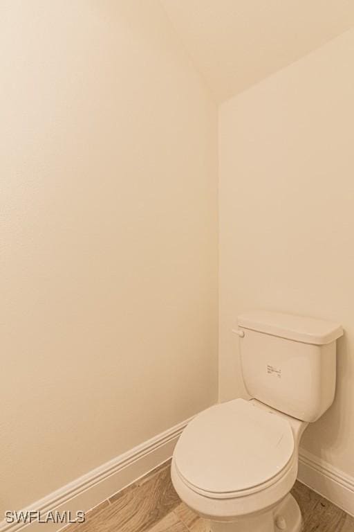 bathroom featuring wood-type flooring, vaulted ceiling, and toilet