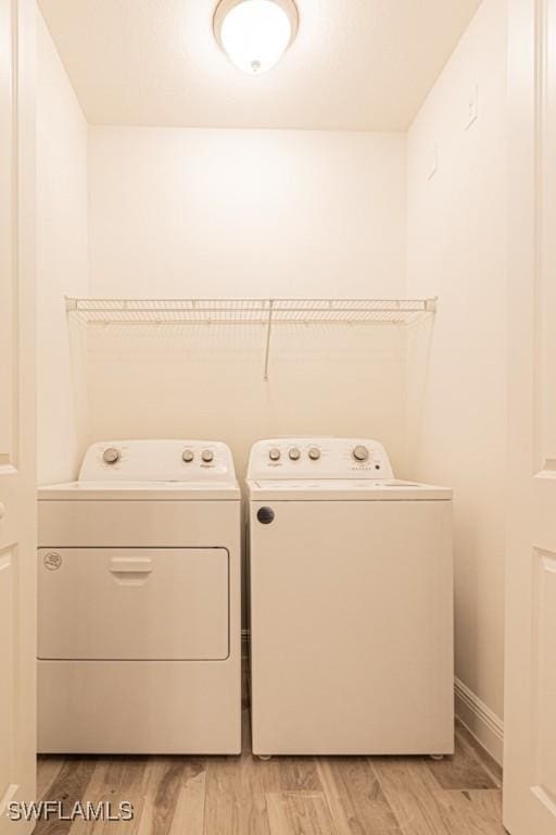 laundry area with light hardwood / wood-style floors and washer and clothes dryer