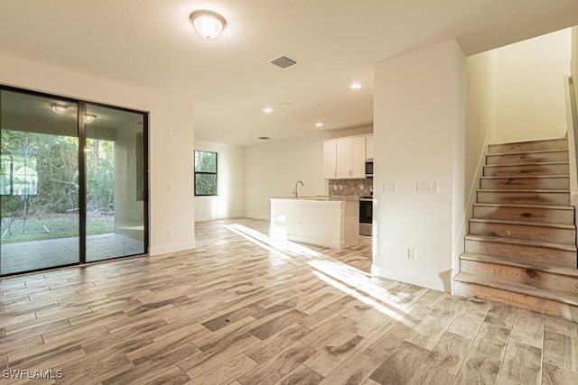 unfurnished living room featuring light wood-type flooring and sink