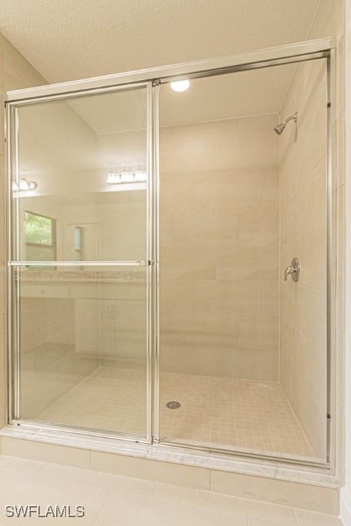 bathroom featuring a shower with shower door and a textured ceiling