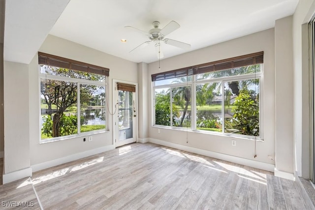 empty room with plenty of natural light, a water view, and light wood-type flooring