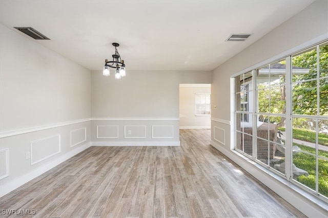 unfurnished room featuring a chandelier and light wood-type flooring