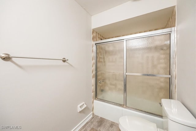 bathroom featuring toilet, shower / bath combination with glass door, and hardwood / wood-style floors