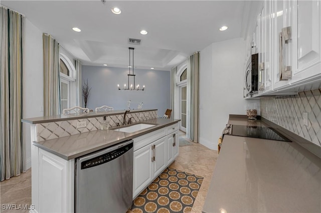 kitchen with stainless steel appliances, decorative light fixtures, sink, a raised ceiling, and white cabinets