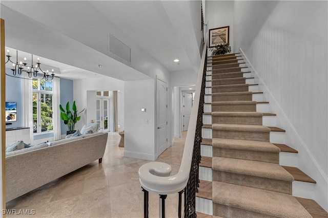 stairs featuring a chandelier