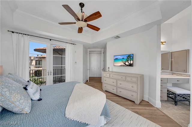 bedroom featuring ornamental molding, access to outside, light hardwood / wood-style floors, and a raised ceiling