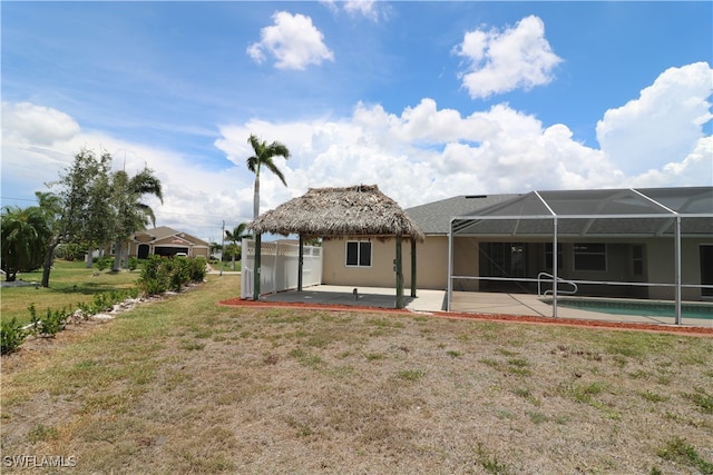 rear view of house featuring a patio, a yard, and a lanai