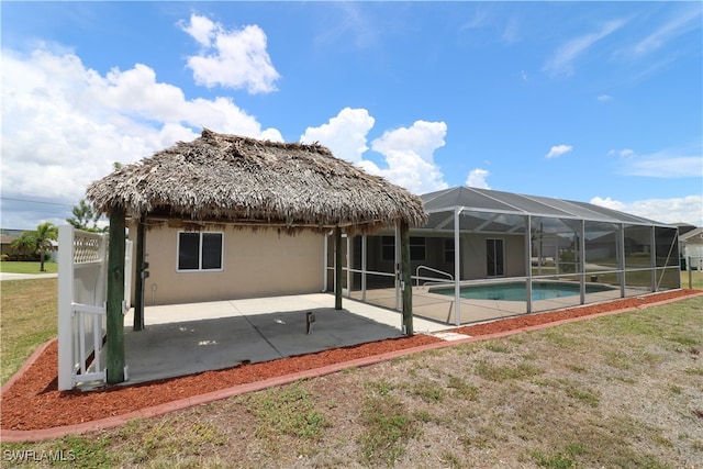 back of house featuring a lawn, a patio, and a lanai