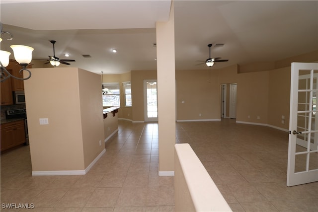 tiled spare room with ceiling fan with notable chandelier