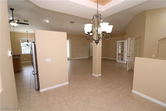 unfurnished dining area featuring light tile patterned flooring, ceiling fan with notable chandelier, and a raised ceiling