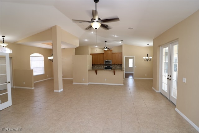 unfurnished living room with ceiling fan with notable chandelier, a healthy amount of sunlight, french doors, and light tile patterned floors